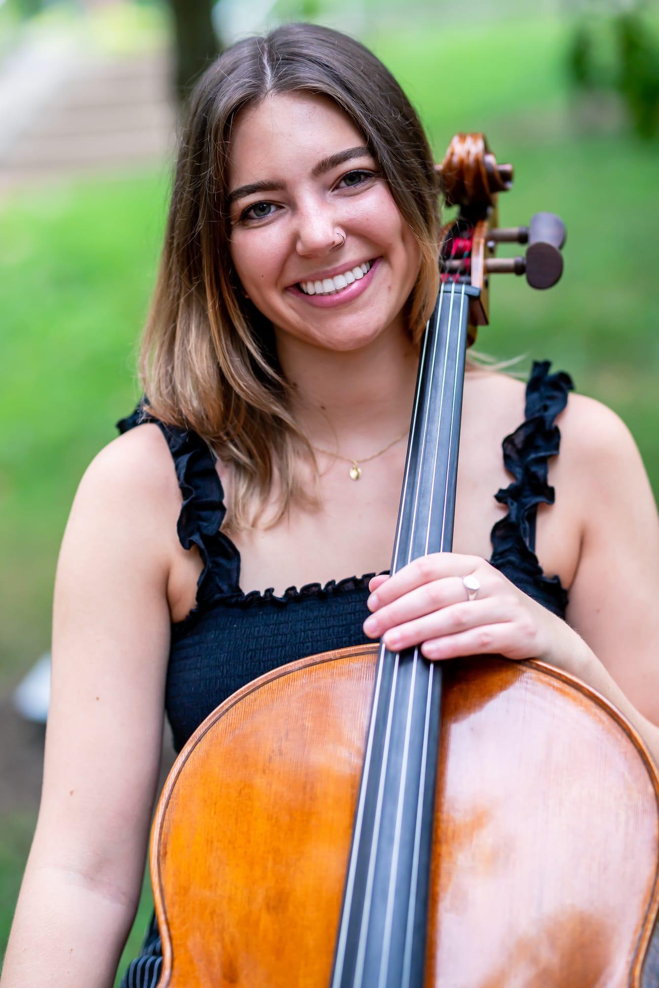 Olivia Hunt smiling outdoors with her cello